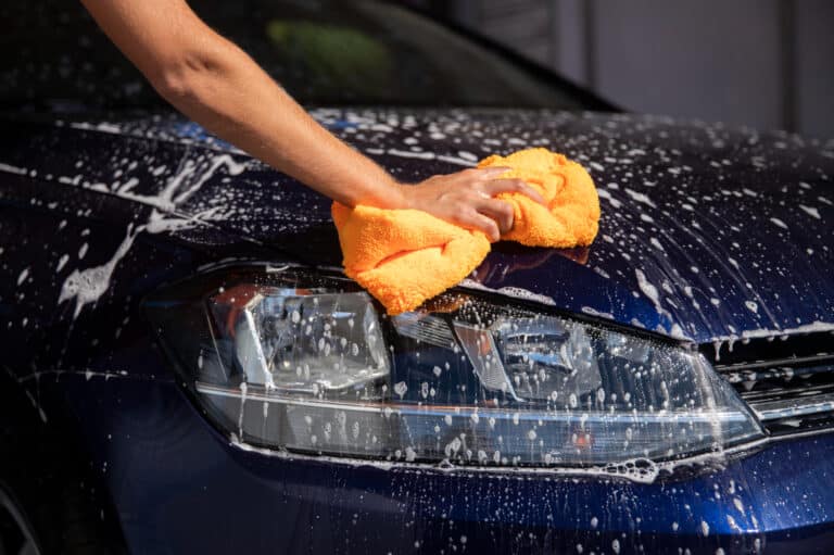 nettoyage phares voiture : main nettoyant un phare de voiture avec citron et bicarbonate de soude